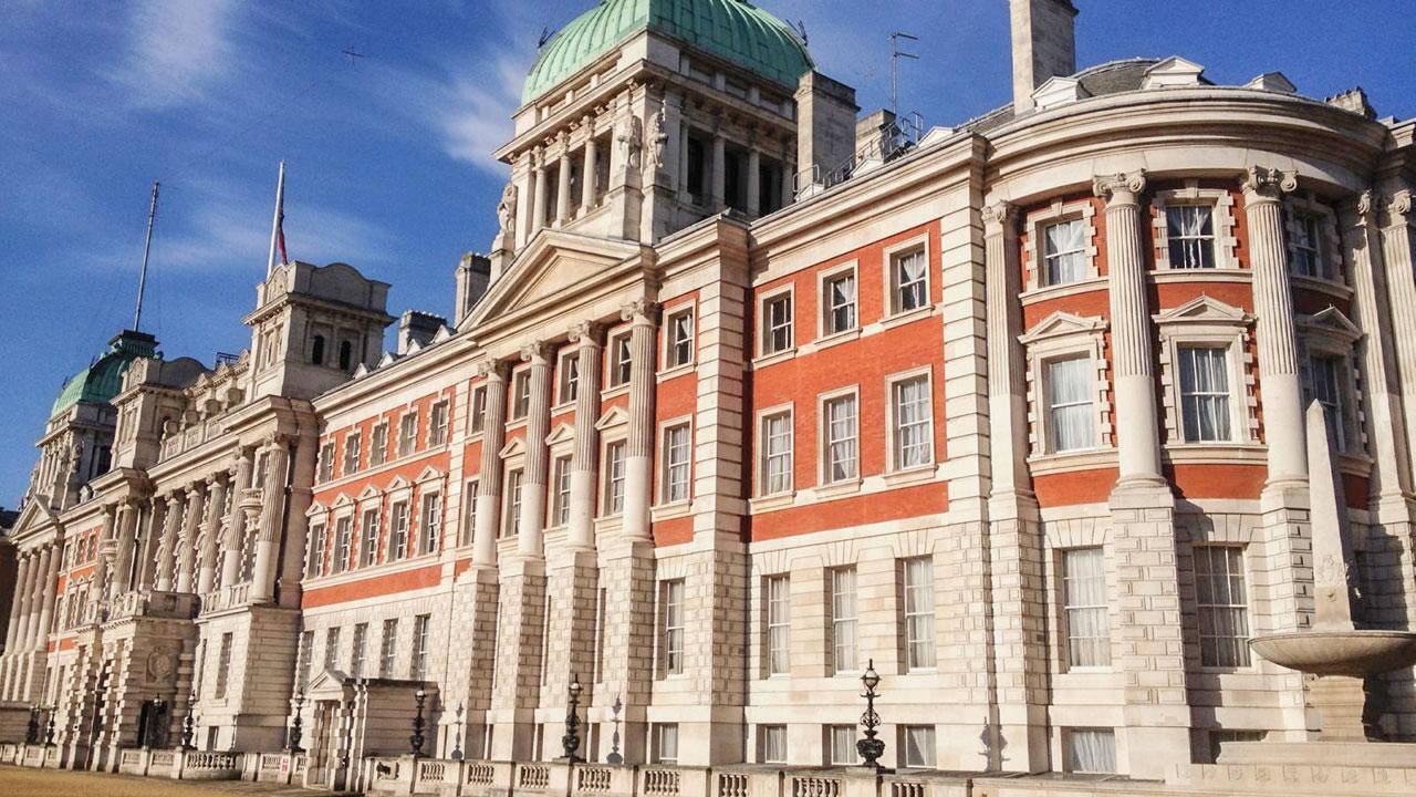 Large multi-story government building featuring gray and red bricks and multiple columns