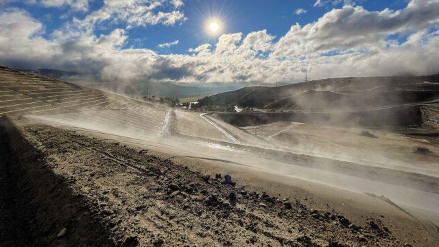 View of a landfill with a blue sky, clouds, and shining sun in the background